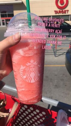 someone holding up a pink drink with a green straw