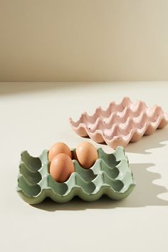 two egg trays with eggs in them sitting on a table next to each other