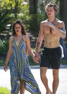 a shirtless man and woman walking down the street