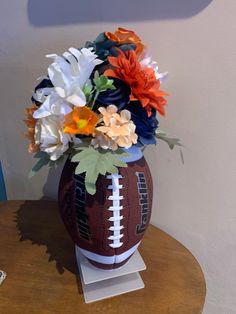 a football vase with flowers in it sitting on a table