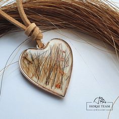 a heart - shaped pendant hangs on a rope next to some dried grass and straw