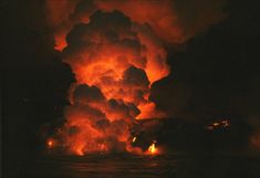 a large fire is coming out of the sky over water at night with bright orange lights