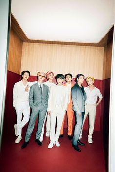 a group of men standing next to each other in front of a red carpeted room