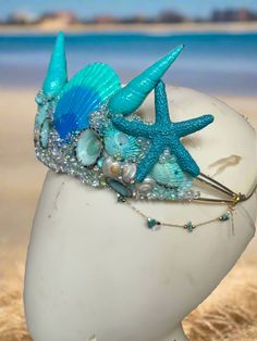 Shimmery Shells Bluesy Mermaid Crown by The Head Mistress Hand-painted shells: Each shell is meticulously hand-painted to capture the beauty of the ocean. Sparkling glitter: Add a touch of sparkle and magic to your mermaid look. Bubble beads: Delicate bubble beads adorn the crown, resembling underwater treasures. Natural moonstone chains: The crown is embellished with natural moonstone chains for an ethereal touch. Available in bold and pastel color palettes: Choose your favorite color palette t Diy Mermaid Crown, Mermaid Look, Bubble Beads, Fantasy Crown, Watercolor Mermaid, Mermaid Crown, Diy Crown, Fabric Photography, Simple Skincare Routine