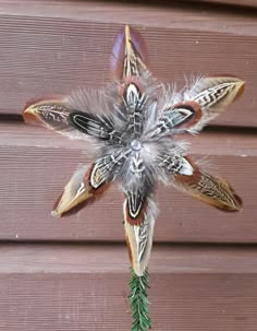 a flower made out of feathers on the side of a building with pine needles sticking out of it