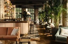 a living room filled with furniture next to a bar and potted palm tree in the corner