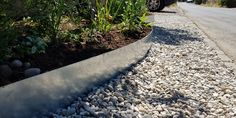 a car parked on the side of a road next to a gravel and grass bed