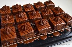 there are many pieces of chocolate cake on the cooling rack with melted chocolate icing