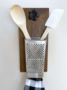 two wooden spoons are attached to a metal holder with a black and white checkered napkin