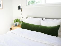 a bed with white sheets and green pillows