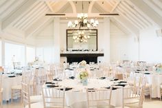 a room filled with tables and chairs covered in white tablecloths next to a chandelier