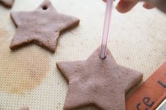 someone is decorating some cookies with pink icing and star decorations on the cookie sheet