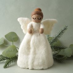 a white angel figurine sitting on top of a green plant