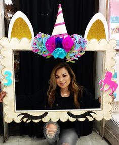 a woman sitting on the floor in front of a photo frame with flowers and unicorn ears