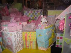 many gift bags are stacked on top of each other and wrapped in pink, blue, yellow and white paper