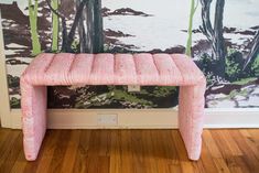 a pink bench sitting in front of a wall