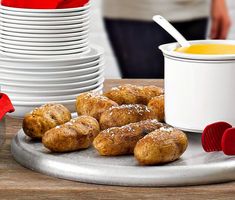 several pastries are on a plate next to some cups and saucers with spoons