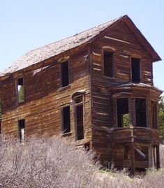 an old wooden house sitting in the middle of a field