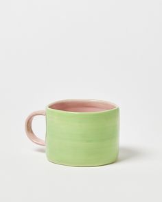 a green and pink mug sitting on top of a white table