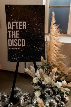 a sign that says after the disco next to some silver balls and pamy plants