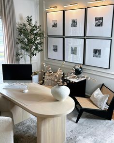 a white table sitting in the middle of a living room with pictures on the wall