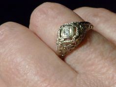 "A lovely early 19th century gold filagree ring. The under gallery is a lattice design punctuated with four blossoms and leaves.The diamond is set into a white gold diamond shape which is framed with braces on each side that are incised with circles and lines. Four rectangular openwork spaces around the setting add to its design. Ring size: 5.5 US, K 1/2 UK, 10 Japan, China, S. America Dimensions: face of ring approx. height 5/16 \" (7.94mm )of face center width 9/16 \" (14.29mm) Weight: approx. Ornate Diamond-cut Filigree Ring, Antique Diamond White Jewelry With Intricate Design, Antique Yellow Gold Diamond Ring With Intricate Design, Ornate Brilliant Cut Jewelry For Formal Events, Ornate Brilliant Cut Jewelry For Formal Occasions, Antique Filigree 14k Gold Diamond Ring, Antique Gold Filigree Diamond Cut Ring, Antique Yellow Gold Filigree Ring With Intricate Design, Antique Filigree Ring With Diamond Accents