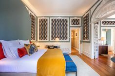 a bedroom with blue walls and white bedding, wooden flooring and colorful pillows