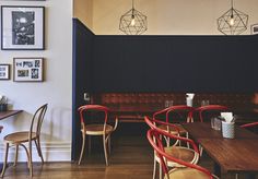 an empty restaurant with red chairs and wooden tables in the center, along with pictures on the wall