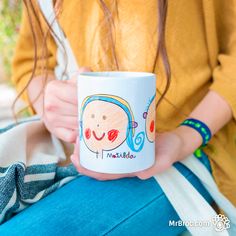 a woman holding a coffee mug with an image of a child's face on it