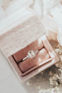 an engagement ring sits in a velvet box on top of some flowers and laces