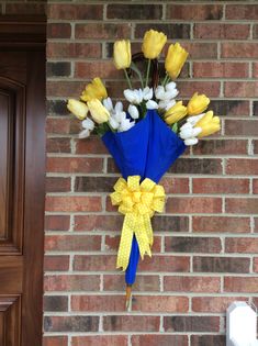 a bouquet of yellow and white tulips hangs on a brick wall next to a door