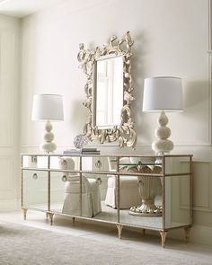 a large mirror sitting on top of a dresser next to a lamp and lampshade