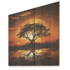 an art piece with a tree in the middle and sunset reflecting on the water behind it