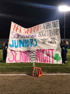 a group of people standing on top of a baseball field holding a sign that reads,