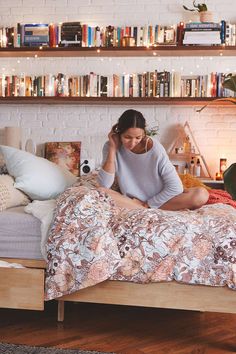 a woman is sitting on her bed talking on the phone