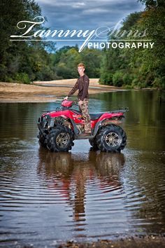 a man riding on the back of a red four - wheeler across a body of water