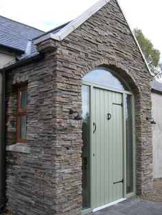 a stone building with a green door and window