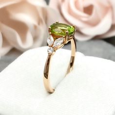 This beautiful ring is made from Solid 14k Rose Gold With Rhodium plating. Ring details- -The Main stone is an oval cut 8mm by 6mm Natural Peridot -Side stones are 4mm by 2mm clear Marquise and 1.3mm Round simulated diamonds -Ring is cast in Solid 14k Rose Gold With Rhodium plating ( 14K Solid Yellow Gold and White Gold also available, please check the drop down menu for more options) -The Total face height of the ring measures 8mms and the band width measures 1.3mms -Each ring is handmade and m Peridot Ring Rose Gold, Green Peridot Rings With Round Stone, Round Cut Peridot Jewelry In Yellow Gold, Round Peridot Three-stone Jewelry, Diamond Leaf Ring, Oval Multi-stone Peridot Gemstones, Expensive Rings, Simulated Diamond Rings, Peridot Ring