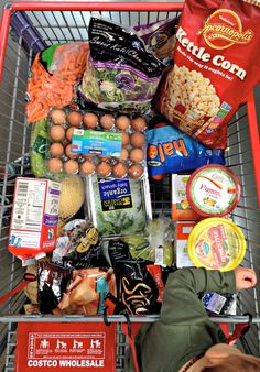 a shopping cart filled with lots of food and condiments in front of a person