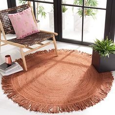 a chair sitting on top of a rug next to a potted plant in front of a window