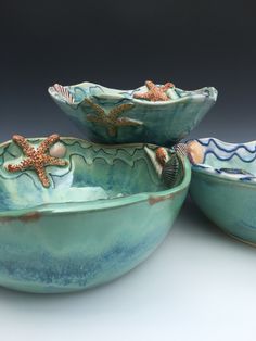 three bowls with starfishs and shells in them