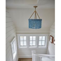 a chandelier hanging from the ceiling in a room with white walls and wood floors