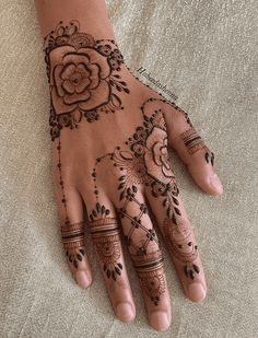 henna tattoo on the palm of a woman's hand, with an intricate flower design