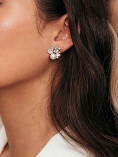 a woman wearing white earrings with flowers on the front and back of her ear,