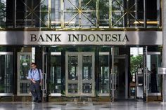 a man standing in front of an entrance to a building with glass doors and the words bank indonesia on it