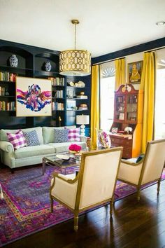 a living room filled with furniture and bookshelves next to a window covered in yellow curtains