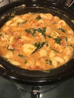 a pot filled with pasta and spinach on top of a stove