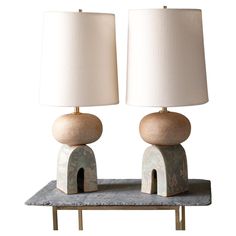 two lamps sitting on top of a table with a white lamp next to each other