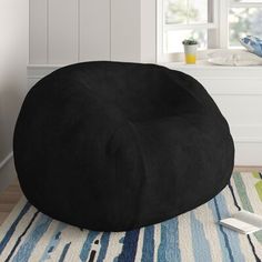 a black bean bag chair sitting on top of a rug next to a white window