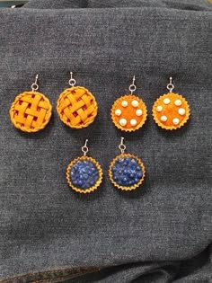 four different colored earrings sitting on top of a piece of cloth next to a pair of jeans